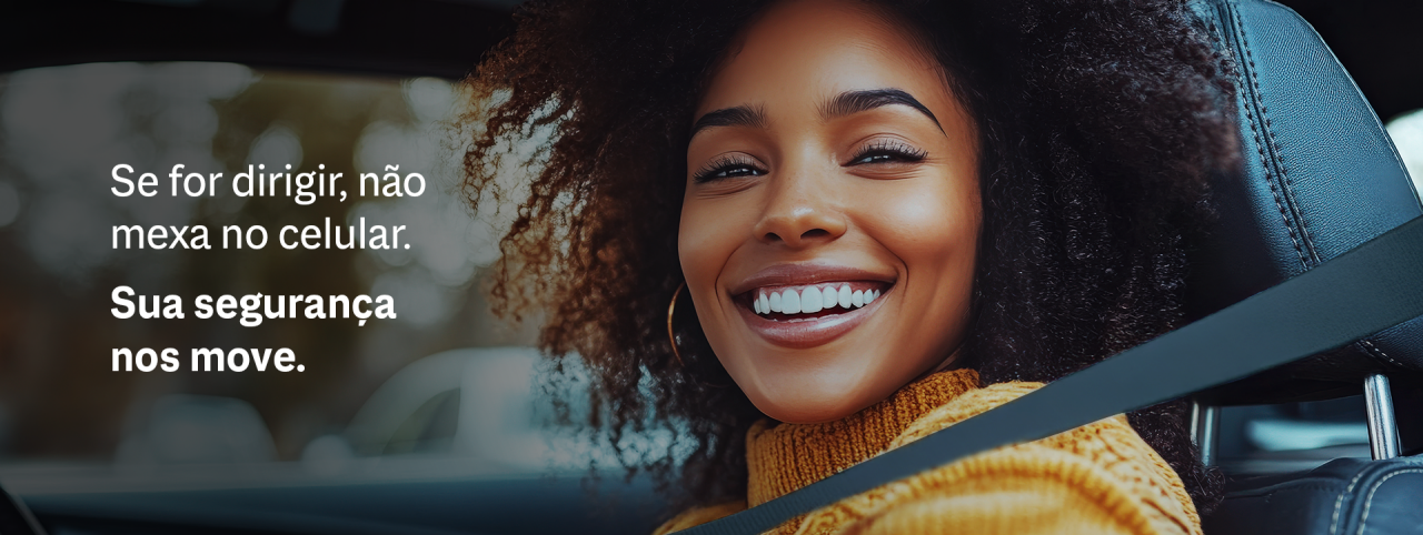Mulher sorridente dirigindo com cinto de segurança, reforçando a mensagem “Se for dirigir, não mexa no celular” sobre segurança no trânsito