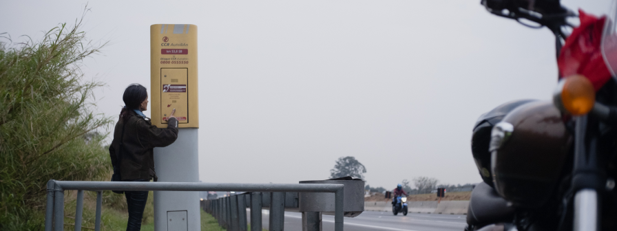 Motoqueiro usando o telefone de emergência (Call Box) na rodovia administrada pela CCR AutoBAn.