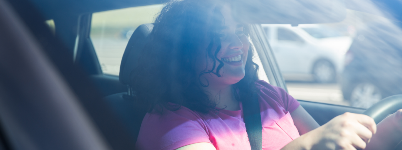 Mulher sorrindo enquanto dirige um carro