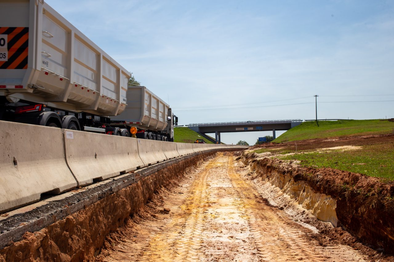 Vista aérea de um trecho em obras de duplicação de uma rodovia, mostrando terraplanagem e solo vermelho exposto.