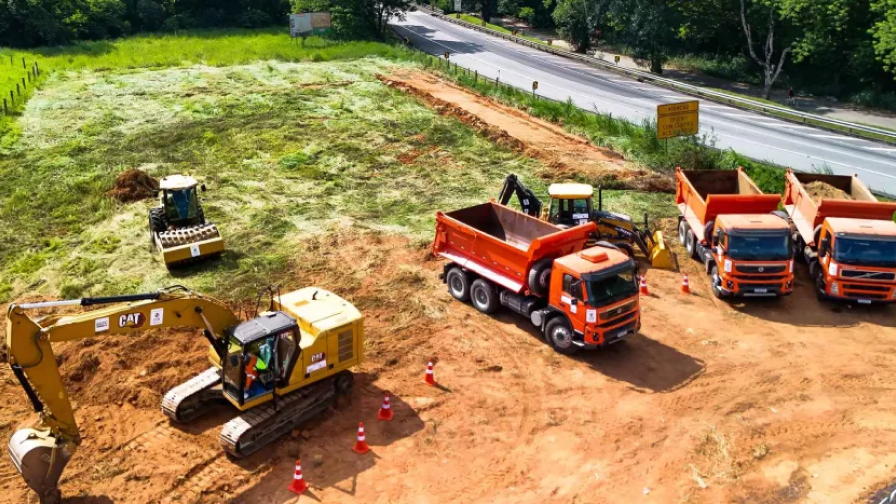 Equipamento de construção em uma estrada de terra próximo a uma floresta, evidenciando a atividade de obras. 
