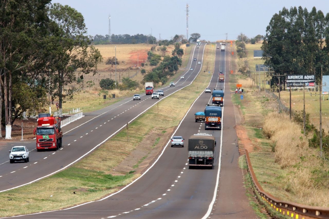 Imagem de trecho da rodovia BR-163/MS duplicada com movimento de carros e caminhões, com canteiro central e acostamento. Fora da rodovia, natureza com árvores verdes ao longo do caminho. Foto: Rachid Waqued