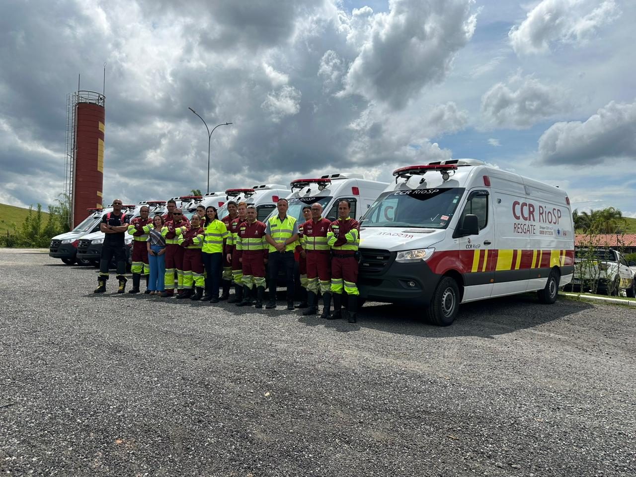 Equipe de paramédicos da CCR Rio SP à frente de suas ambulâncias, sob o céu aberto