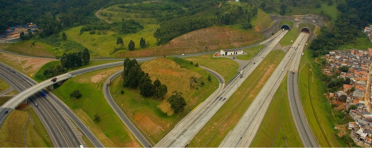 Rodovia de mão dupla administrada pela CCR RodoAnel, com vegetação e edifícios comerciais ao longo das margens