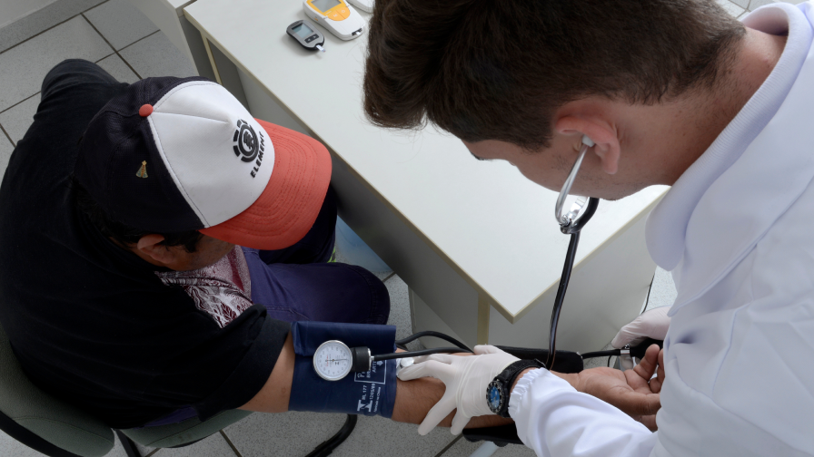 Médico aferindo a pressão arterial de um paciente, motorista de caminhão.
